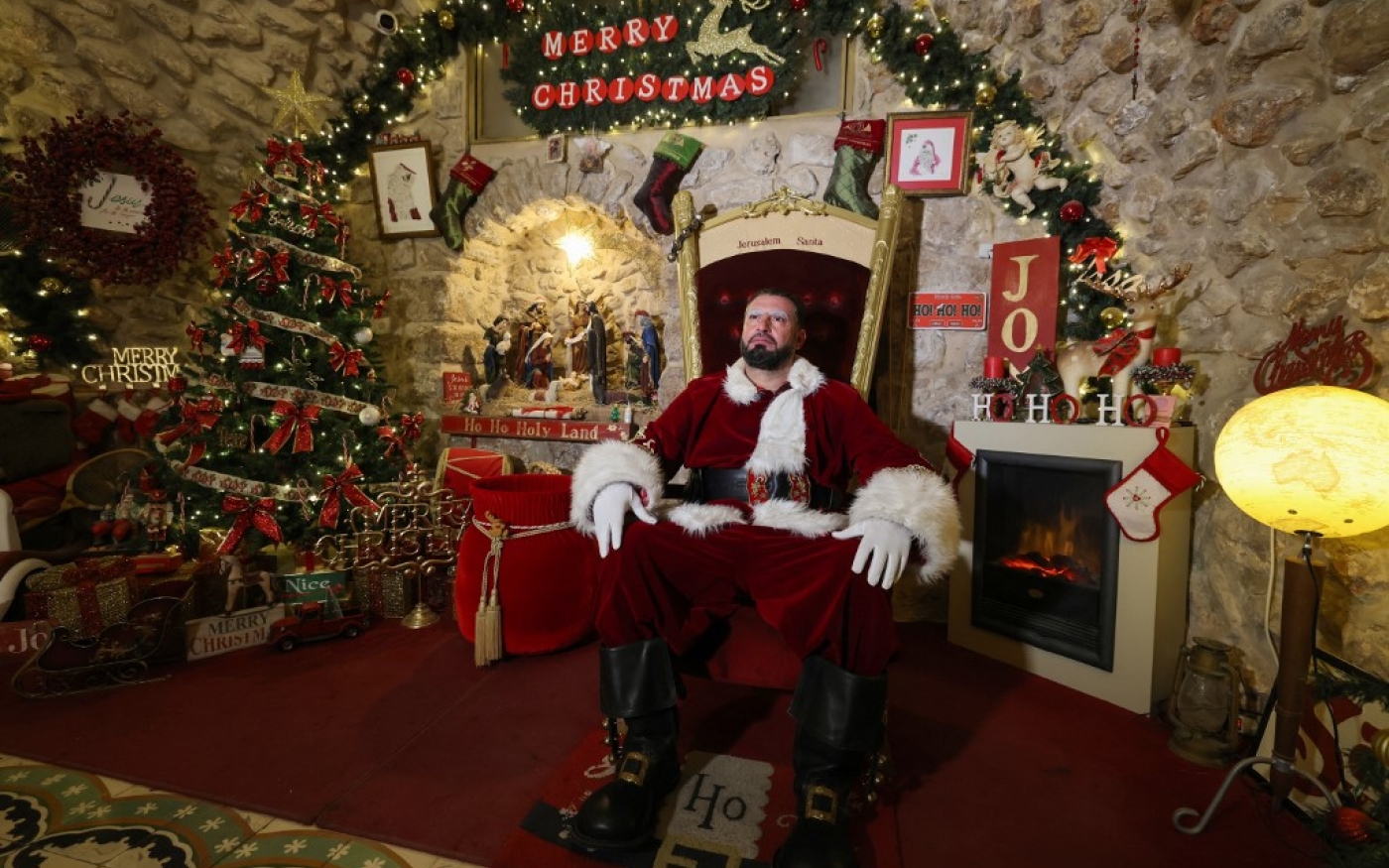 Le Palestinien Issa Kassissieh, habillé en père Noël, pose pour une photo dans la partie de sa maison transformée en Maison du père Noël, dans la Vieille ville de Jérusalem, quelques semaines avant les prochaines vacances de Noël, le 1er décembre 2022 (AFP/Ahmad Gharabali)