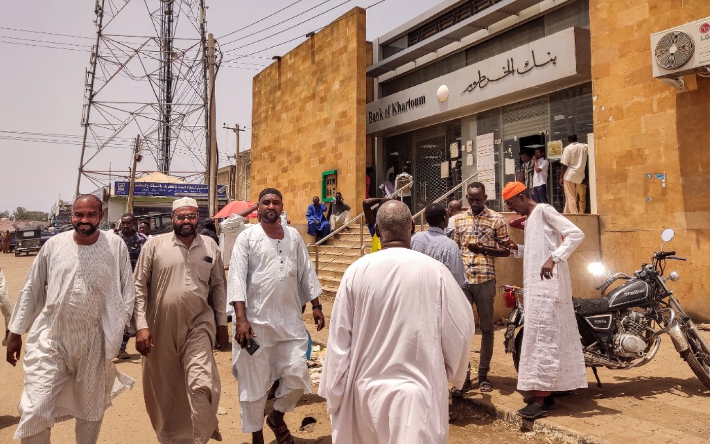 Des Soudanais marchent devant une succursale de la Banque de Khartoum, dans la ville de Gedaref, dans l’est du Soudan, le 9 juillet 2023 (AFP)