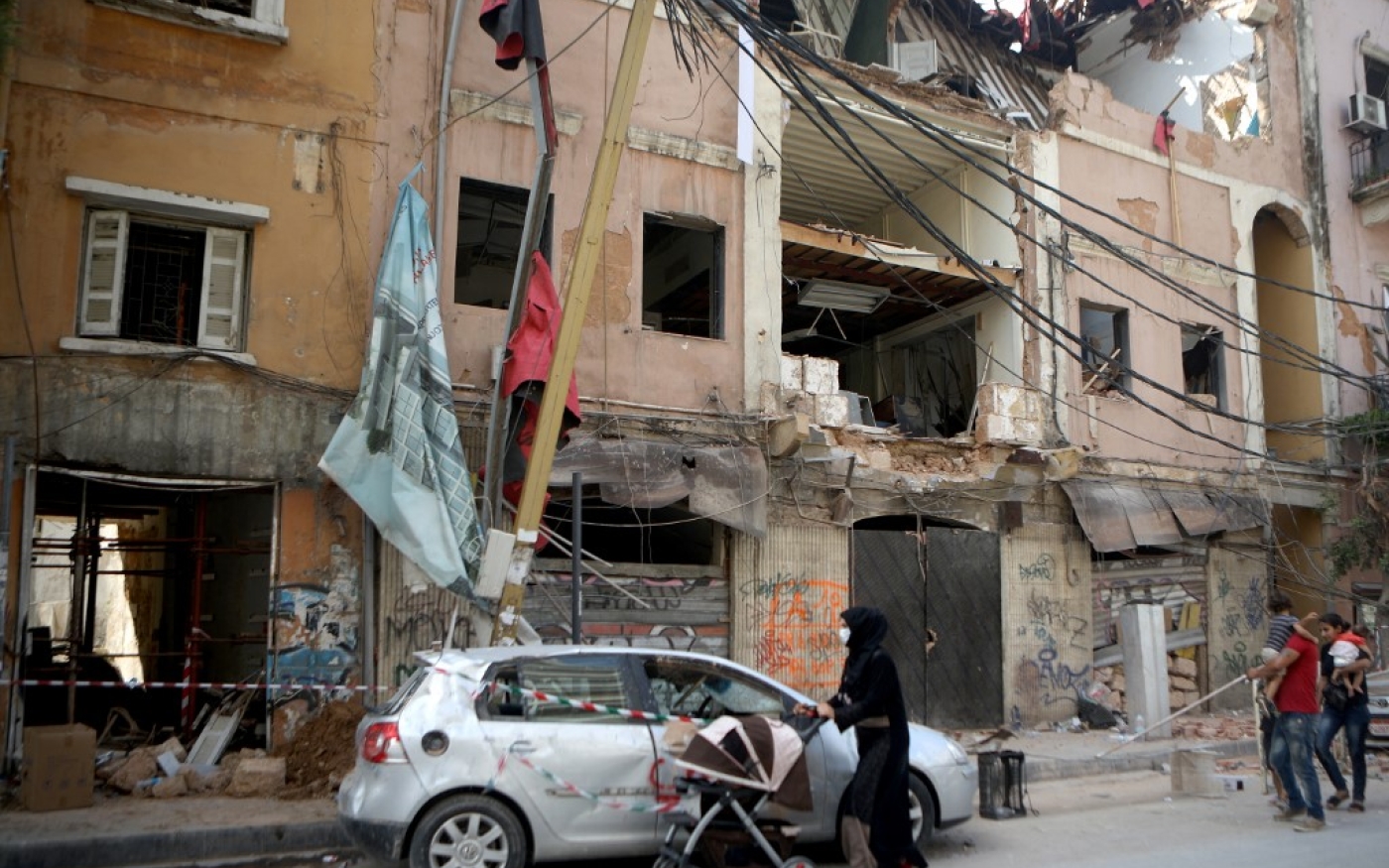 Des réfugiés syriens passent devant des bâtiments endommagés dans le quartier partiellement détruit de Mar Mikhael, à Beyrouth, le 13 août 2020 (AFP)