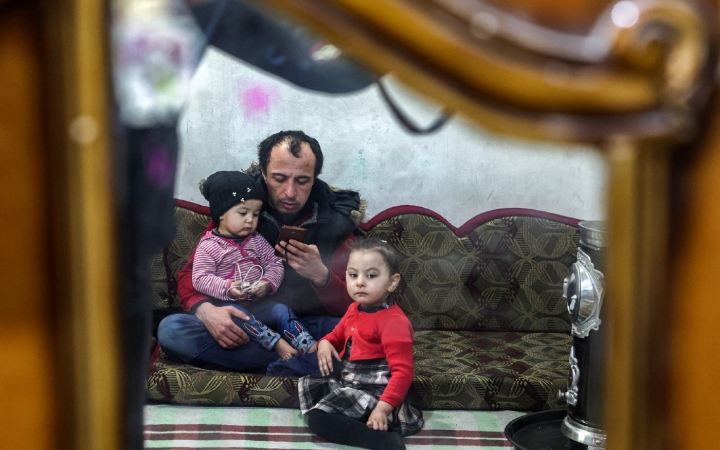 Islam Shakhbanov est assis avec ses enfants chez lui à Idleb, en Syrie, le 29 janvier 2023 (AFP/ Omar Hajj Kaddour)