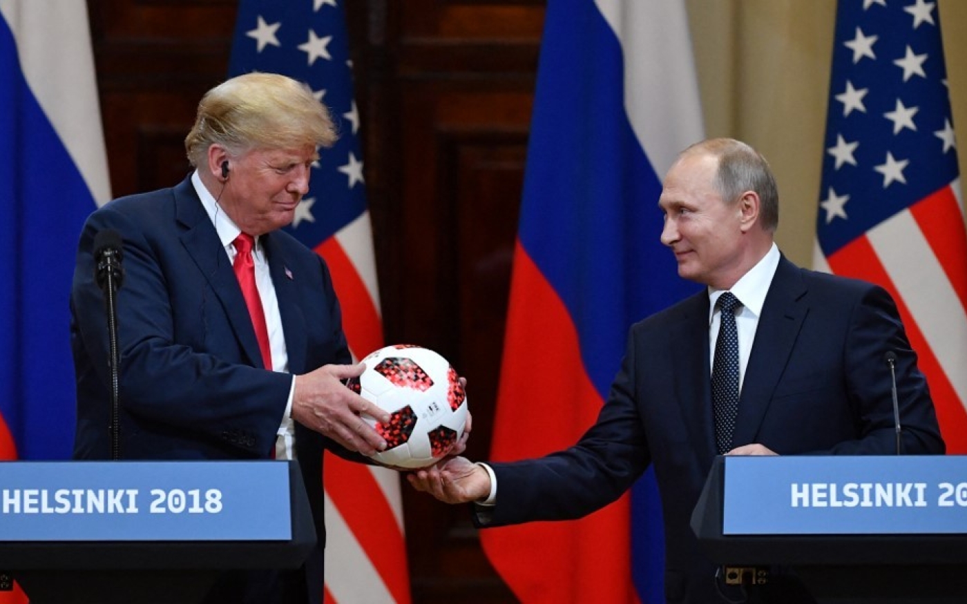 Le président russe Vladimir Poutine offre un ballon de la Coupe du monde 2018 à Donald Trump, alors président américain, lors d’une conférence de presse conjointe à Helsinki, en juillet 2018 (AFP)