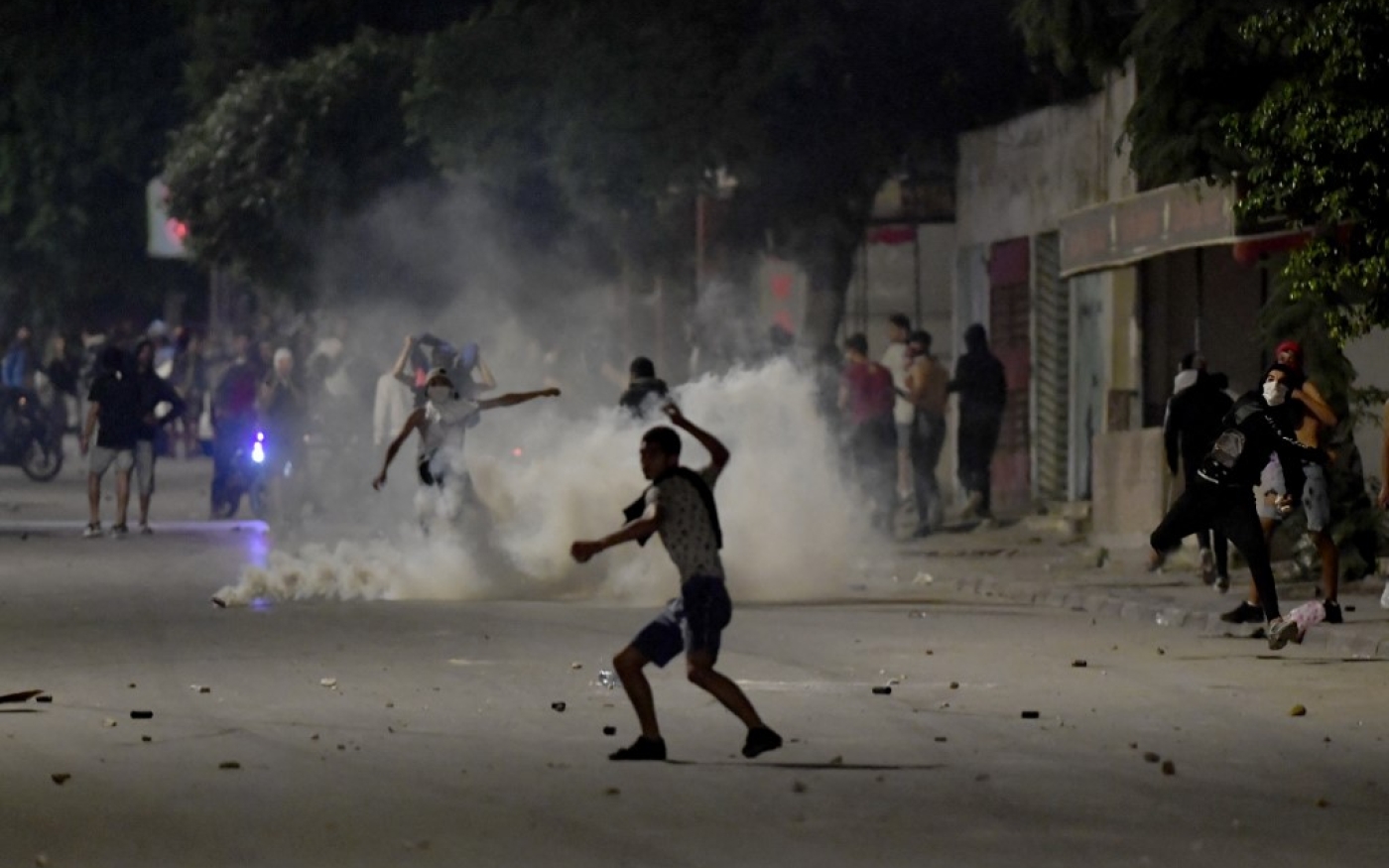 Des manifestants lancent des pierres sur les forces de sécurité à Ettadhamen, le 14 octobre 2022, le jour où un Tunisien de 24 ans est décédé à l’hôpital des suites de blessures subies fin août après un accident lors d’une poursuite policière (AFP/Fethi Belaid)