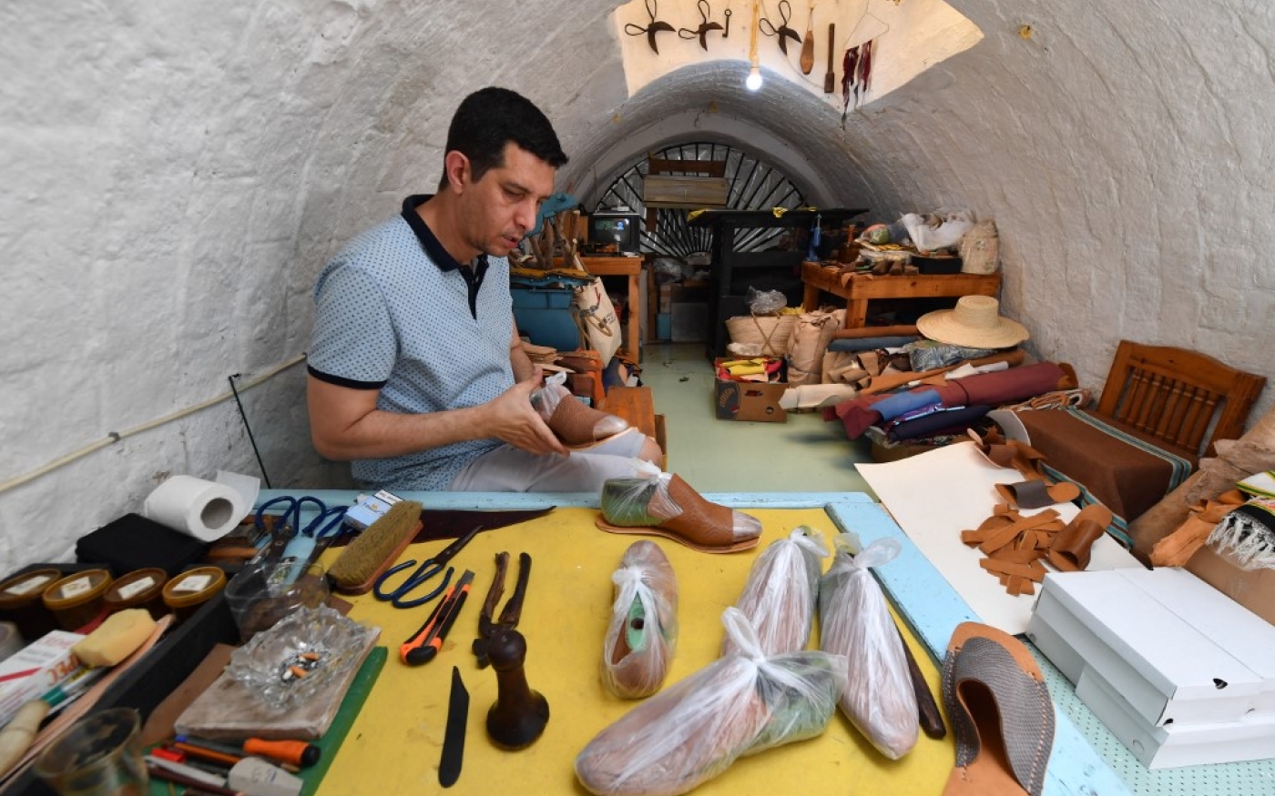 L’artisan tunisien Souhail Fitouri fabrique des chaussons traditionnels en cuir, « balgha », dans son atelier de l’ancienne médina de Tunis, le 21 mai 2022 (AFP/Fethi Belaid)