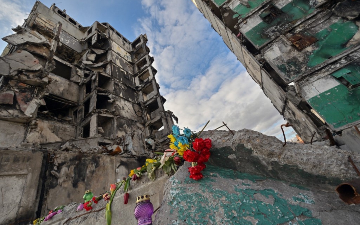 Des fleurs et des bougies ont été posées sur les décombres d’un immeuble détruit par des frappes demissiles russes, dans la région de Kyiv, le 6 mars 2023 (AFP/Sergei Supinsky)