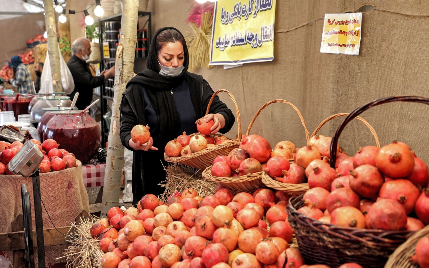 Une cliente inspecte des grenades dans un marché de Téhéran, en 2021 (AFP/Atta Kenare)