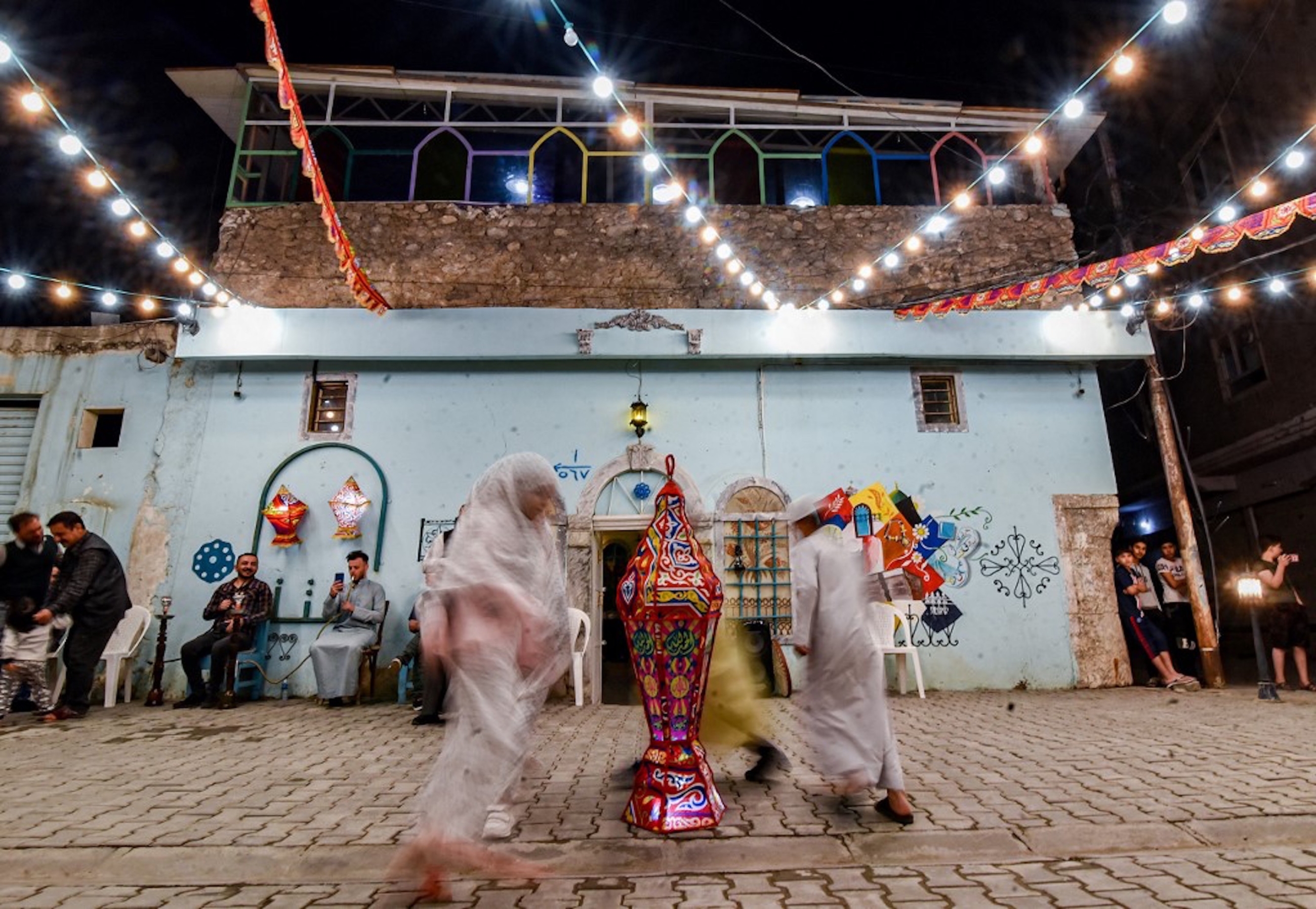 IRAK. Des enfants dansent autour d’une lanterne lors d’une fête de rue organisée par une ONG culturelle locale lors de la première nuit du Ramadan dans la vieille ville de Mossoul, le 13 avril 2021 (AFP)