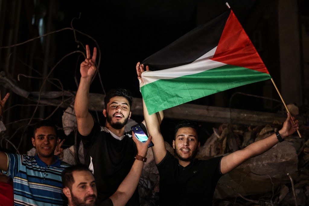 People wave the Palestinian flag and cheer as they celebrate in the street in Gaza City.