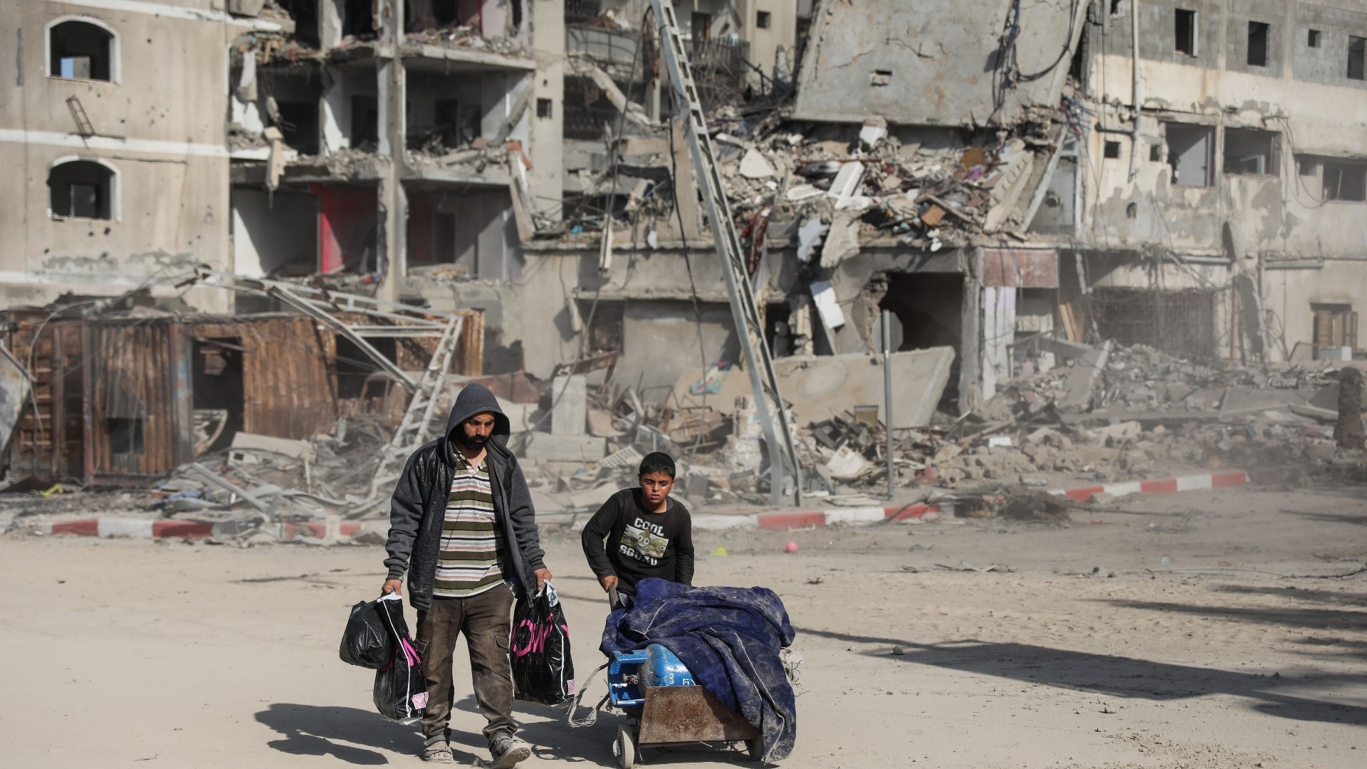 A Palestinian family walking in destroyed neighbourhoods in Gaza City on 24 November 2023 (MEE)