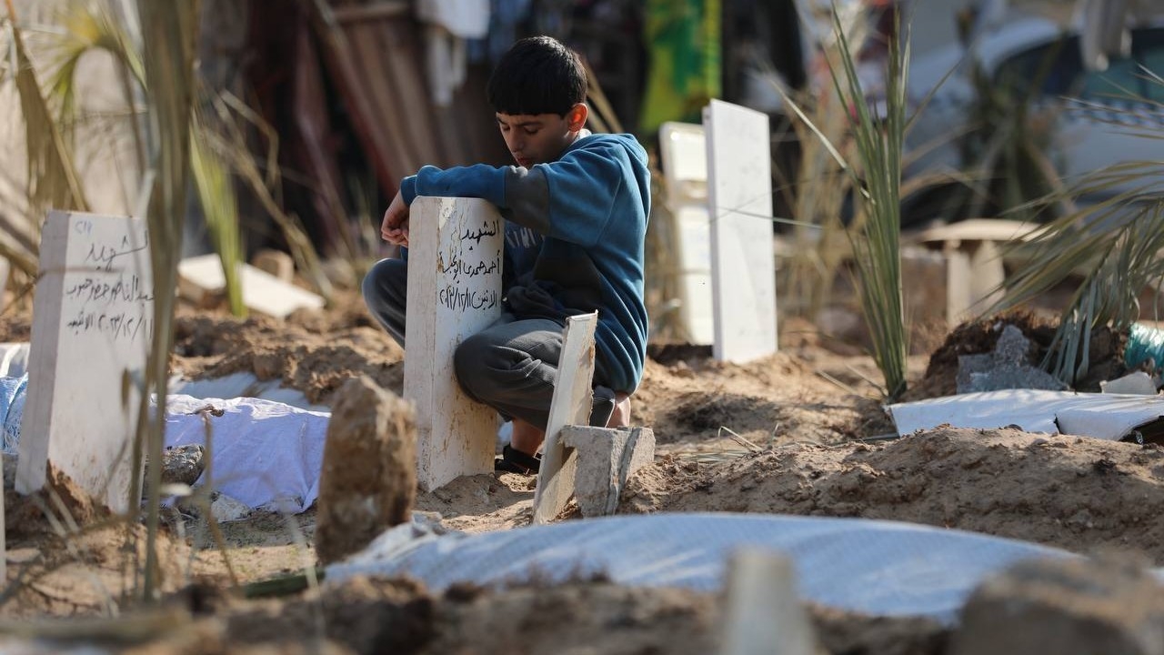 A Palestinian boy hugs the grave of a family member killed in Israeli bombing in Gaza City on 31 December, 2023 (MEE/Mohammed al-Hajjar)