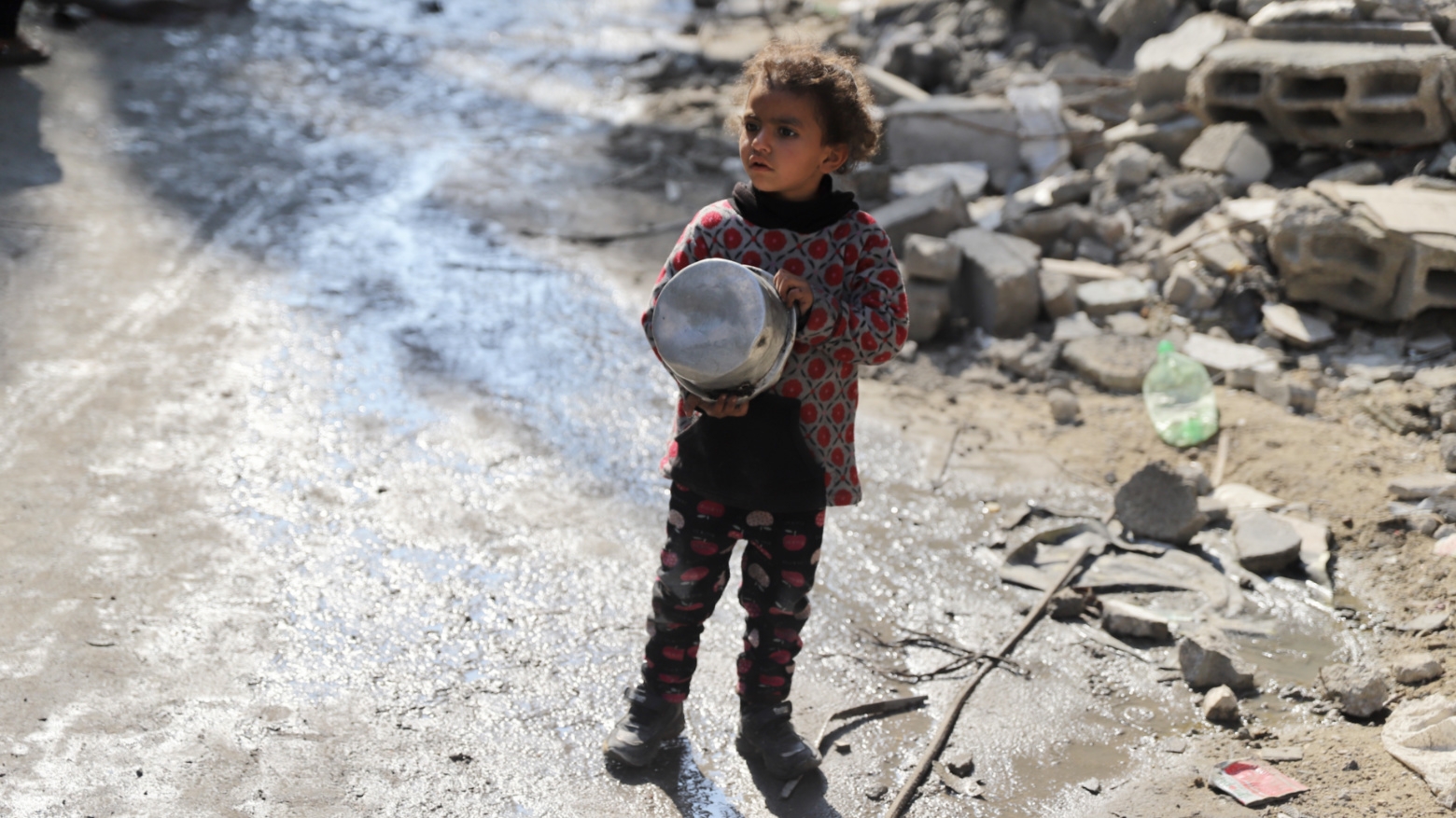 A girl holds her empty food bowl in Gaza City (Mohammed al-Hajjar/MEE).