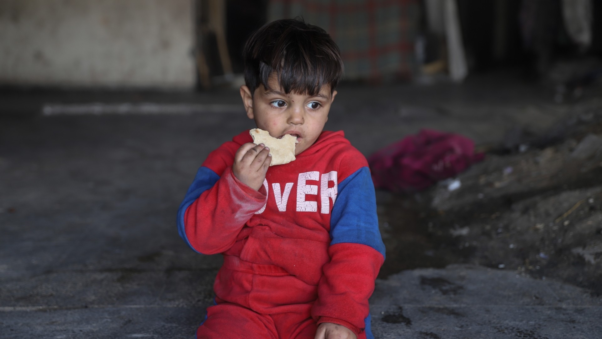 A Palestinian child eats bread in Gaza City during a lull in Israeli air strikes. According to the UN, famine is imminent in Gaza, and could occur any time up to July (MEE/Mohammed al-Hajjar)