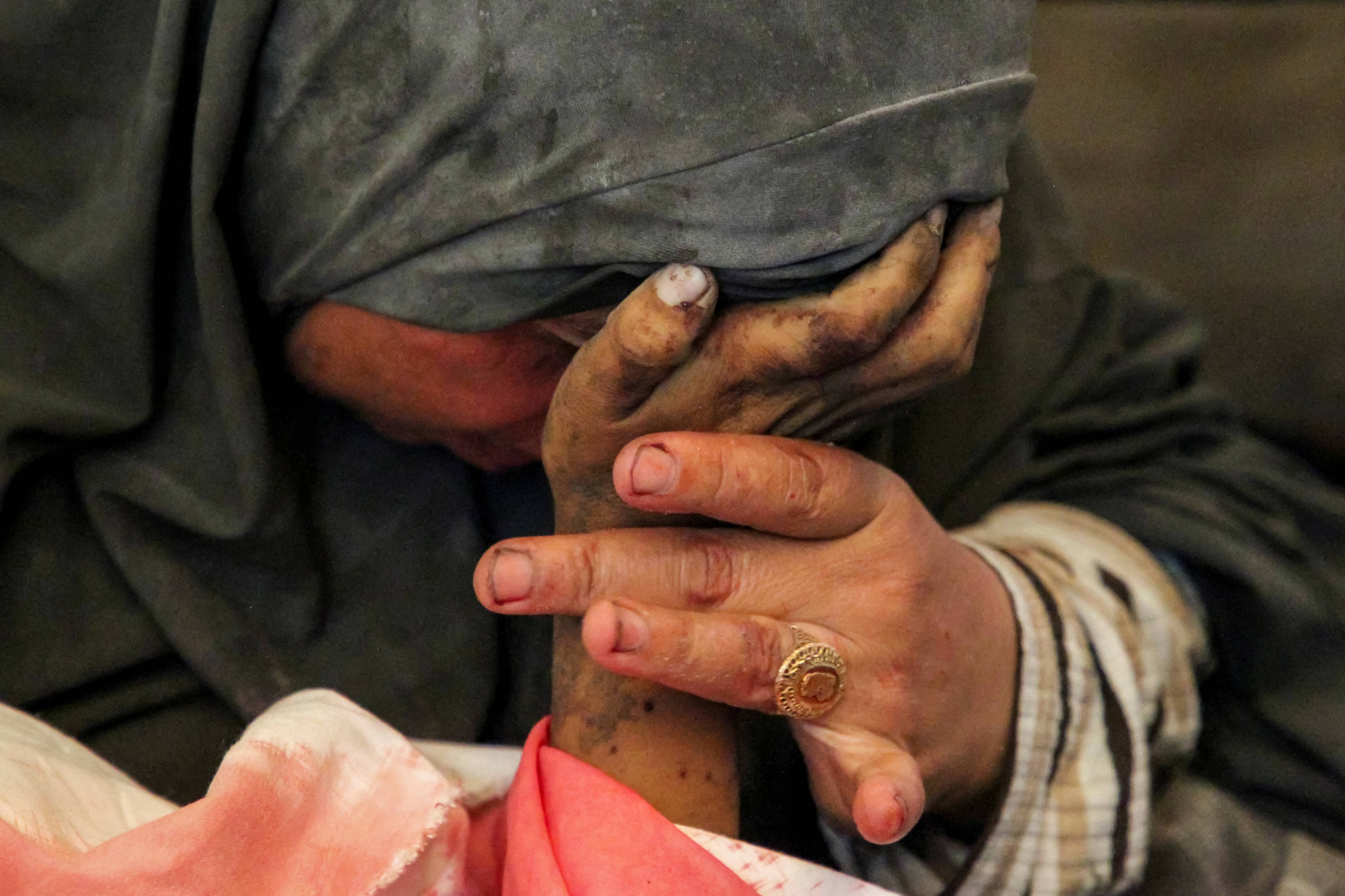 Palestinian woman Buthayna Abu Jazar reacts as she holds the hand of her son Hazma, who was killed in an Israeli strike in Rafah, in the southern Gaza Strip 9 May 2024 (Reuters/Hatem Khaled)