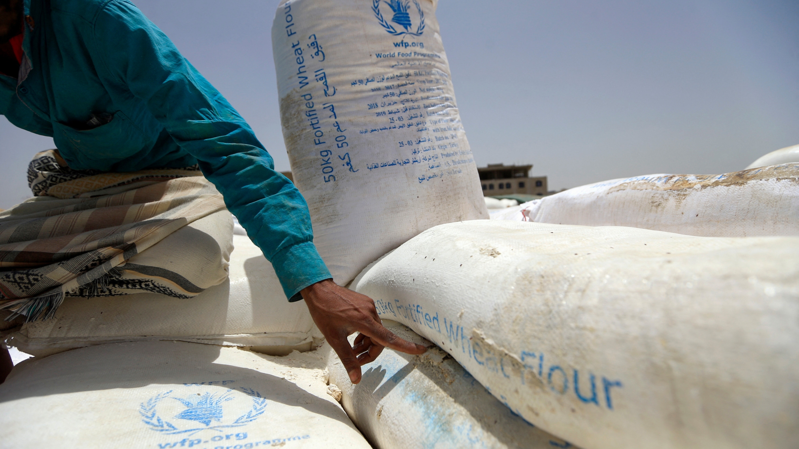 A Yemeni points to a flour bag from the World Food Organisation in the Yemeni capital Sanaa on 23 June 2019 (AFP)