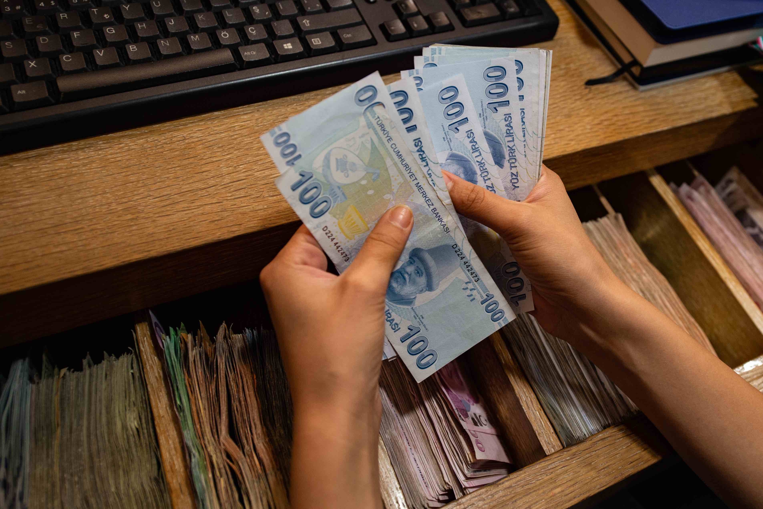 A currency exchange office worker counts Turkish Lira
