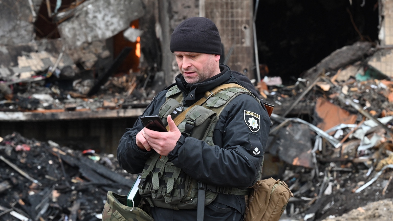 A police officer stands guard at a damaged residential building in the Ukrainian capital Kyiv on 25 February 2022 