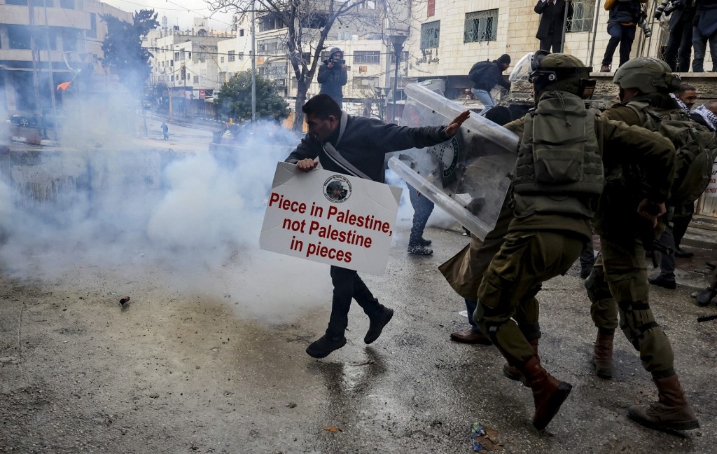Members of the Israeli army chase a Palestinian protester following a demonstration to remember the 1994 Ibrahimi Mosque massacre, in the West Bank's Hebron, on 25 February 2022 (AFP)