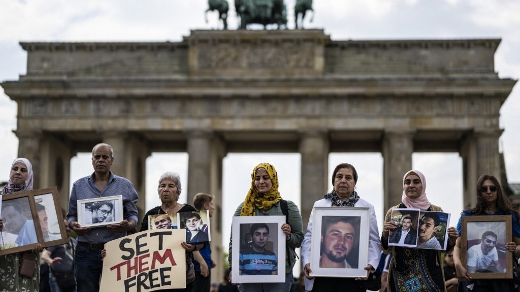 Activists and relatives of Syrians suspected of being detained or disappeared by the Syrian government pose with portraits of missing Syrians during a demonstration in front of Berlin's Brandenburg gate on 7 May 2022.