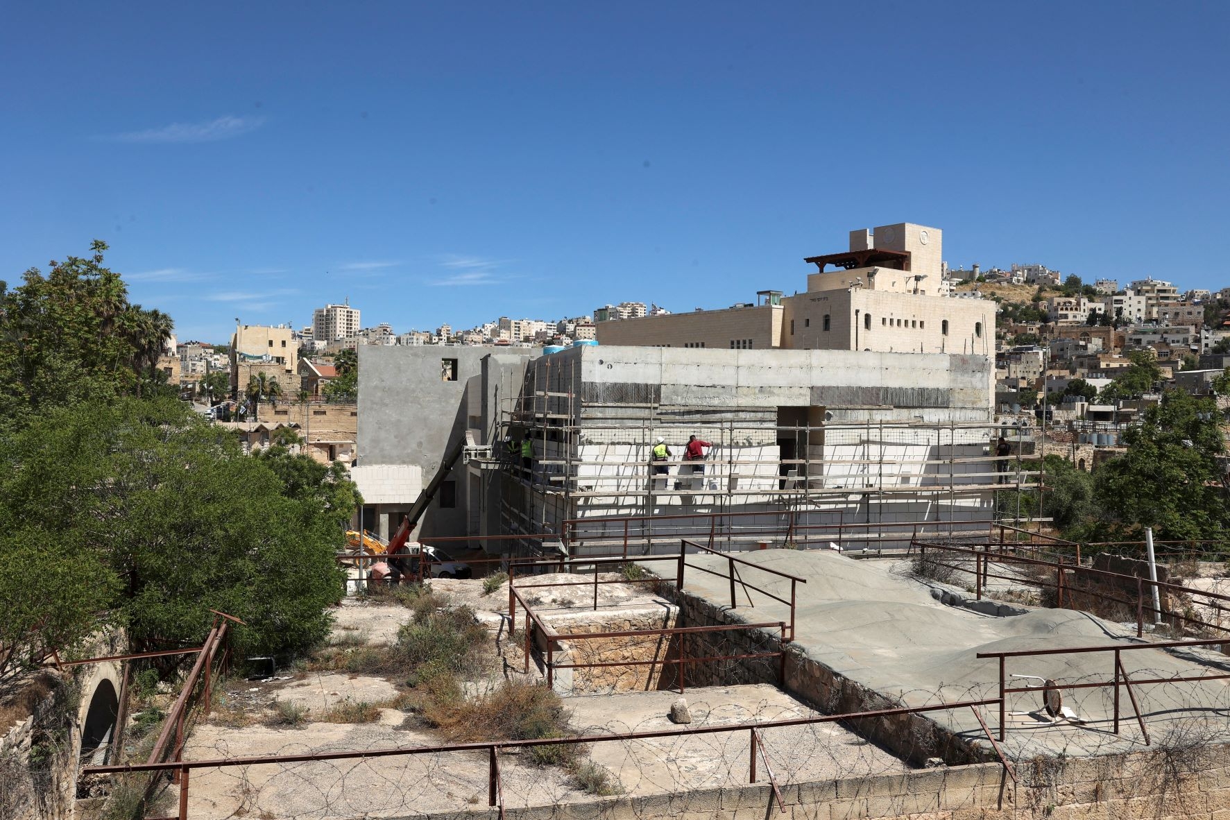 Builders work on new constructions in a settlement zone on a site where the old central bus station for the Hebron Governorate formerly stood on 8 May 2022 (AFP)