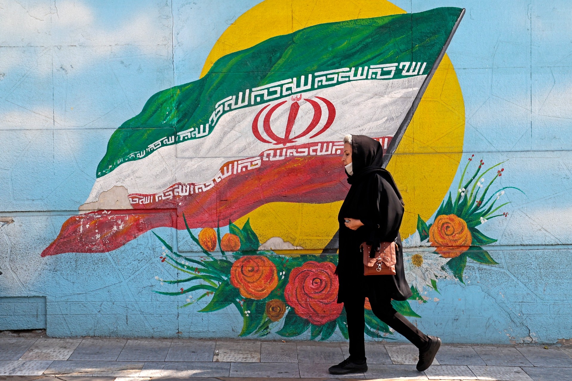 Une femme passe à côté d’une fresque à Téhéran, le 11 octobre (AFP)
