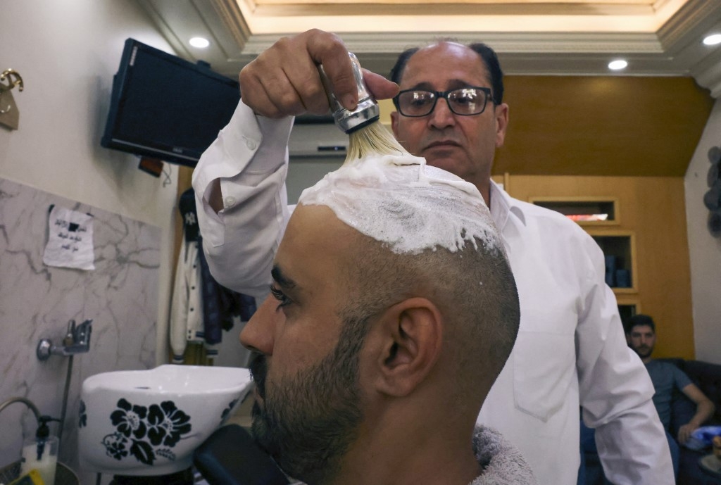 A Palestinian man has his hair shaved at a salon in Hebron city in the occupied West Bank, on 16 October 2022, following a trend which spread on social media in solidarity with a bald-headed Palestinian reported to be behind an attack on an Israeli checkpoint in occupied East Jerusalem (AFP)