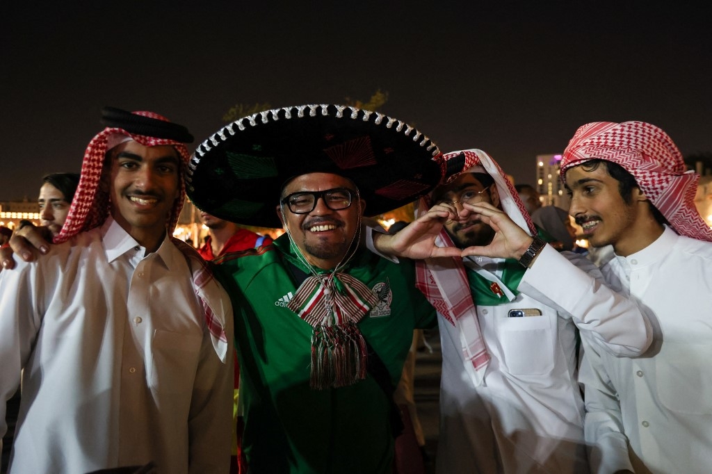 A Mexico fan posing with Saudi Arabia supporters