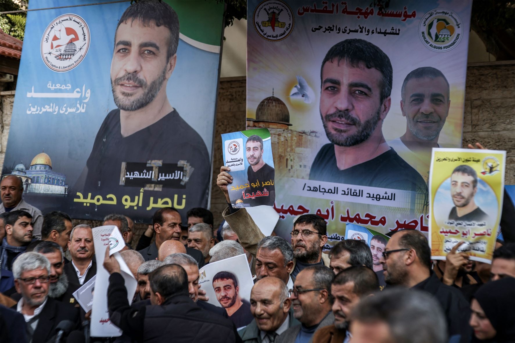 People gather with photos of Palestinian Nasser Abu Hamid for a protest outside the International Committee of the Red Cross (ICRC) mission headquarters in Gaza City on December 20, 2022 (AFP)