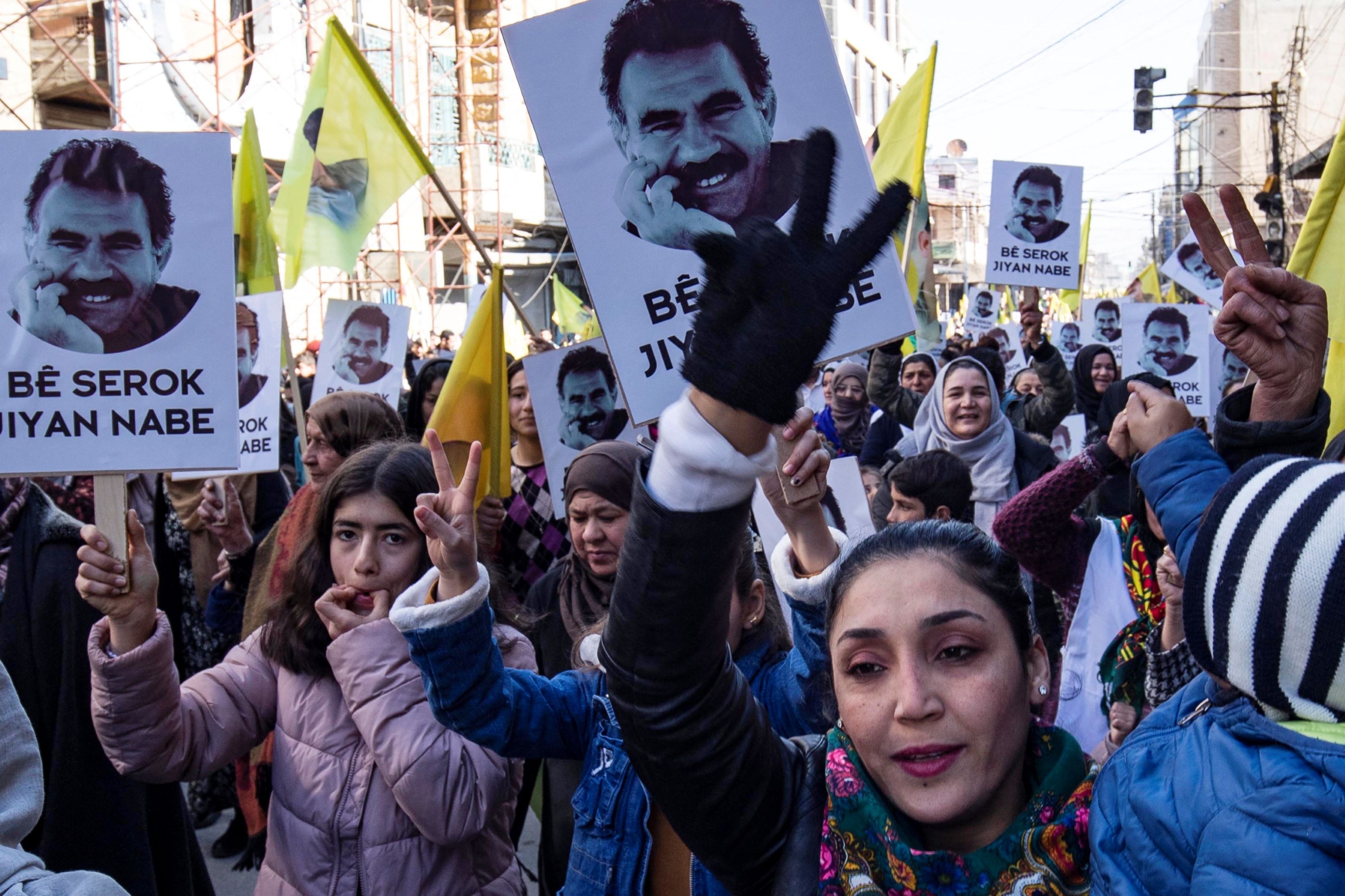 Protesters raise yellow flags and portraits showing the face of Abdullah Ocalan, the leader of the Kurdistan Worker's Party (PKK) -- jailed in Turkey since 1999 -- during a demonstration calling for his release, in the Kurdish-majority city of Qamishli in northeastern Syria on February 15, 2023 (AFP)