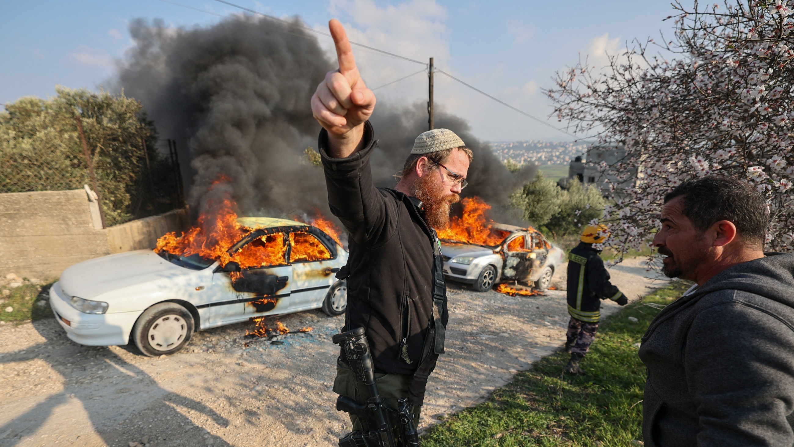 Armed Israeli settler gestures amid confrontations between settlers and Palestinians in Burin village near Nablus in occupied West Bank on 25 February 2023 (AFP)