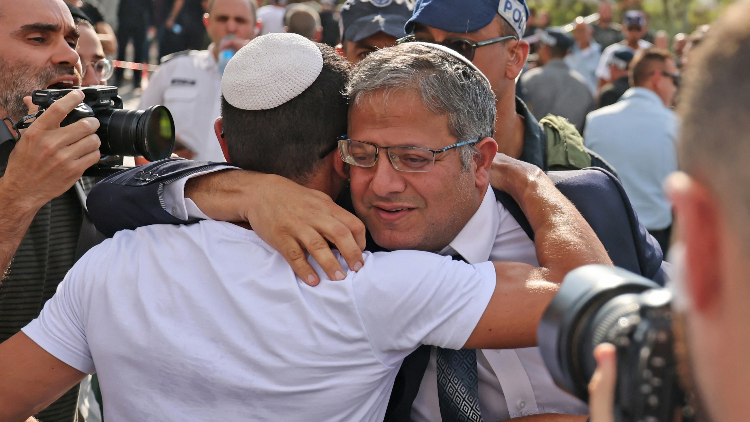 Israel's National Security Minister Itamar Ben-Gvir hugs a supporter as he arrives to the site of a reported attack in the Israeli settlement of Maale Adumim in the occupied West Bank, on 1 August 2023 (AFP)
