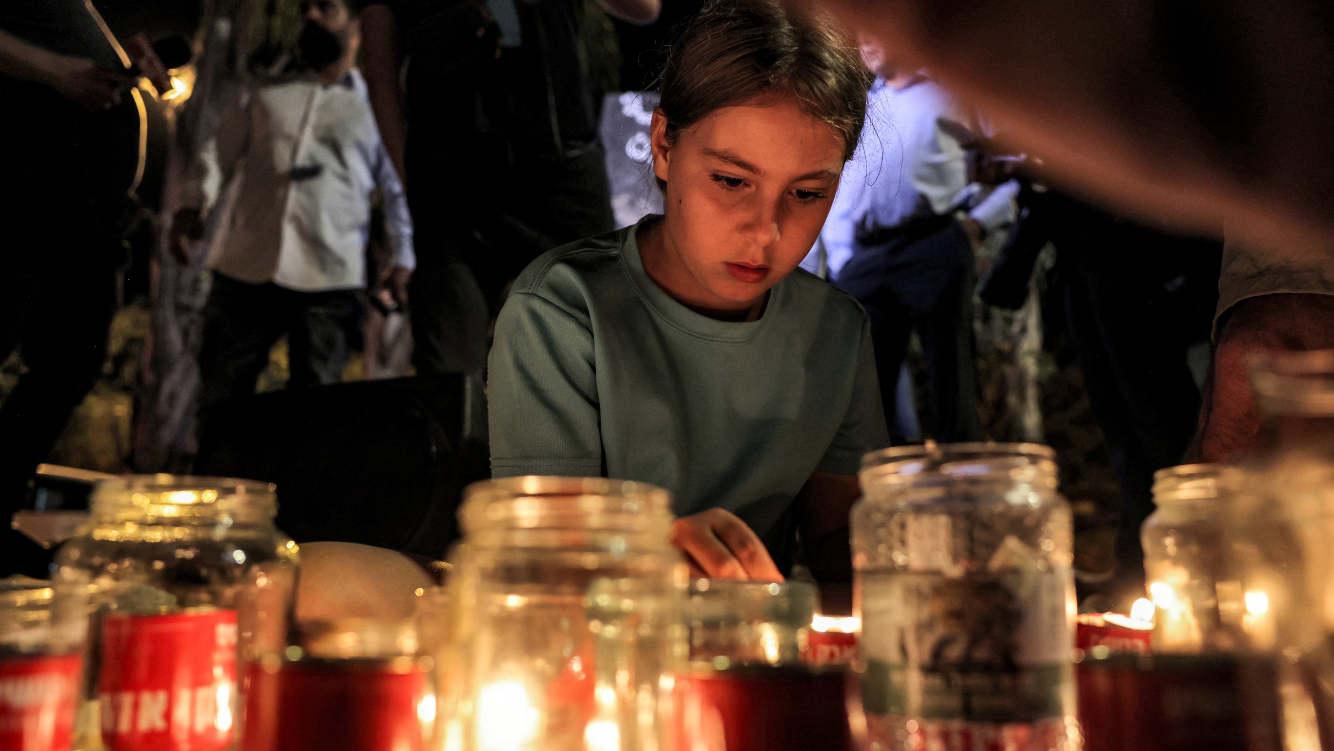 A girl lights candles during a vigil against violence targeting Palestinian citizens of Israel in the town of Basmat Tab'un on 27 September 2023 (AFP)