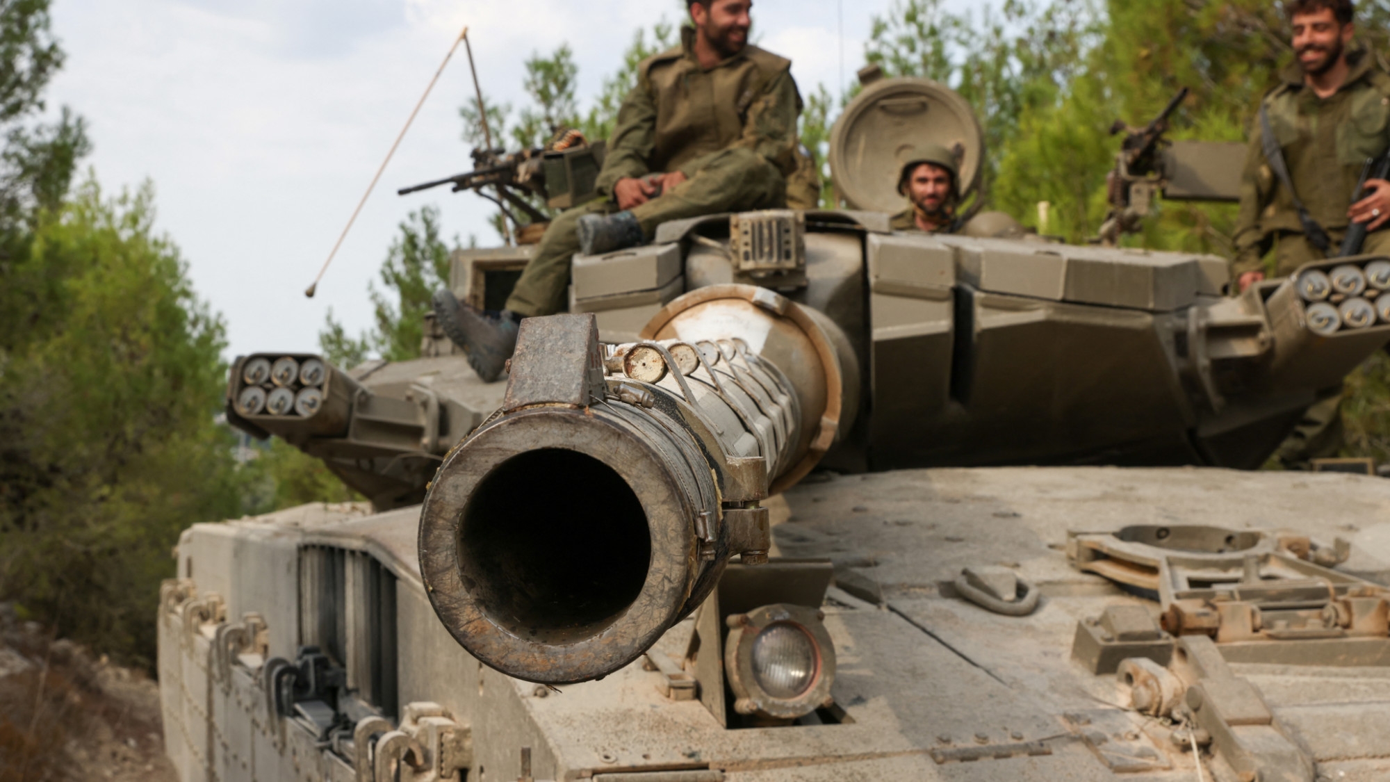 Israeli soldiers ride a Merkava tank in northern Israel on 9 October 2023 (AFP/Jalaa Marey)