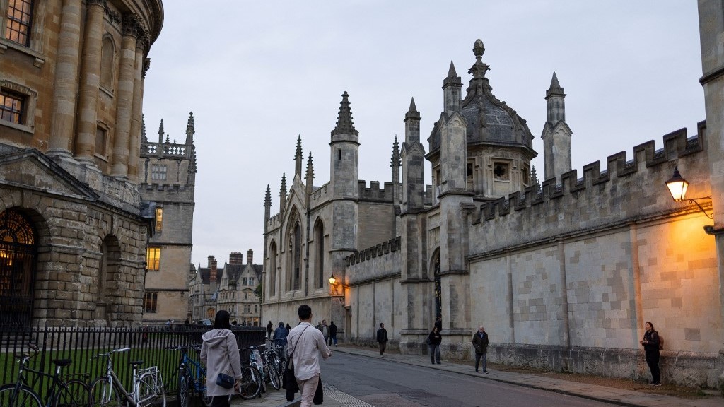 People walk outside the College of All Souls, in Oxford, on October 20, 2023 (Henry Nicholls/ AFP)