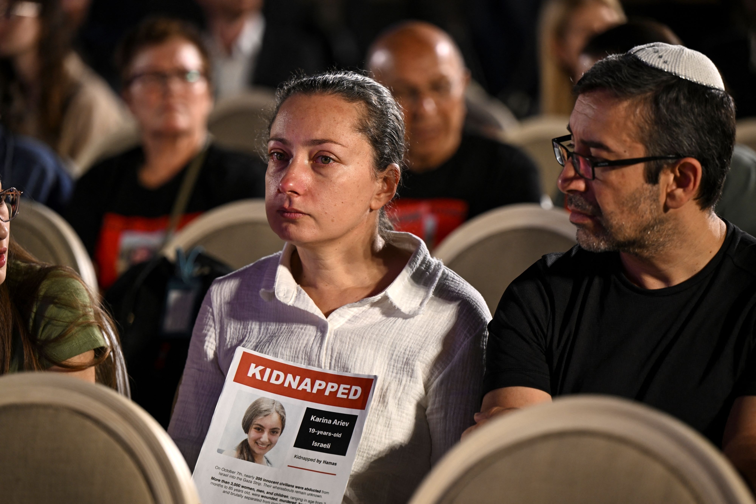 People hold a poster of hostage Karina Ariev as they gather at a spot overlooking the Western Wall Plaza in Jerusalem as they attend the Global Day of Unity and Prayer with Israel’s Hostages and Missing Families Forum (AFP)