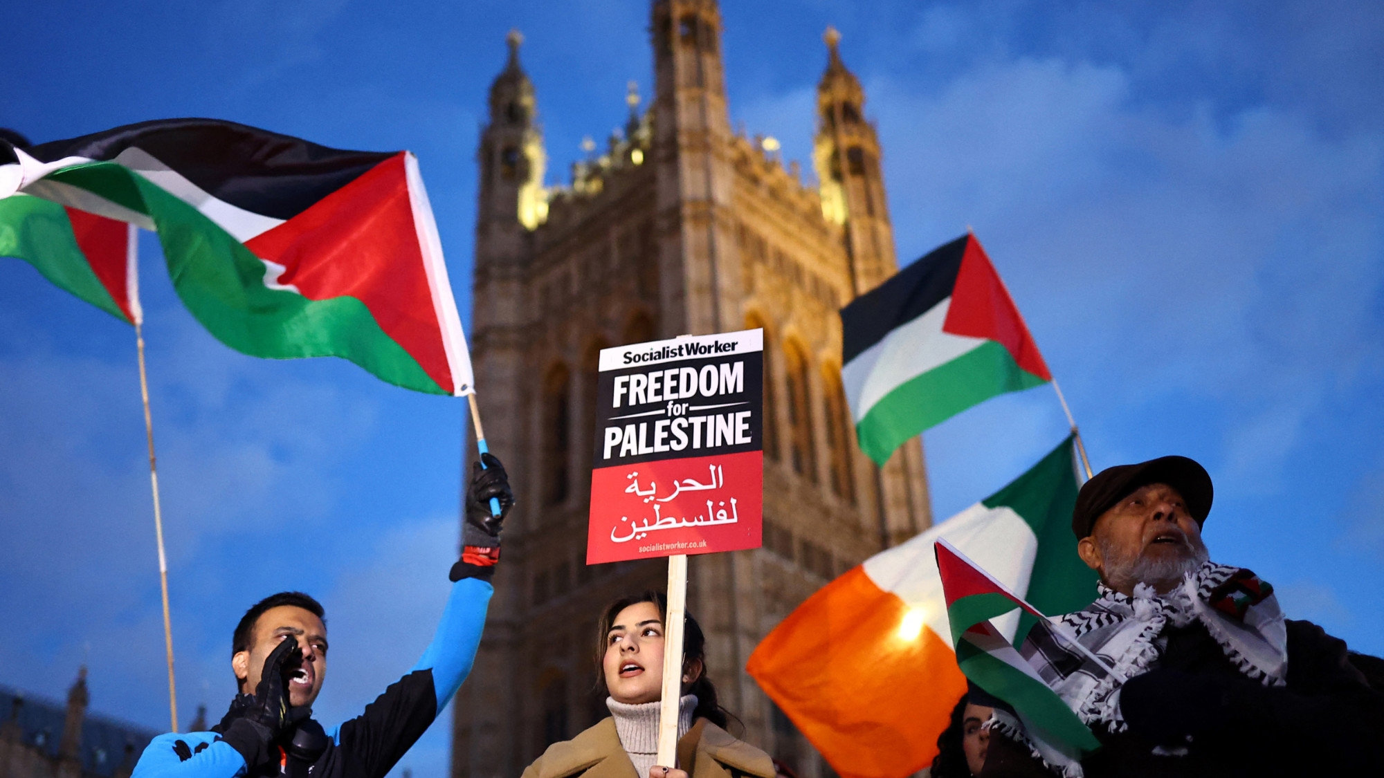 Protesters hold placards and flags as they chant slogans during a rally in support of Palestinians, outside of the Houses of Parliament in central London on 15 November 2023 (AFP)