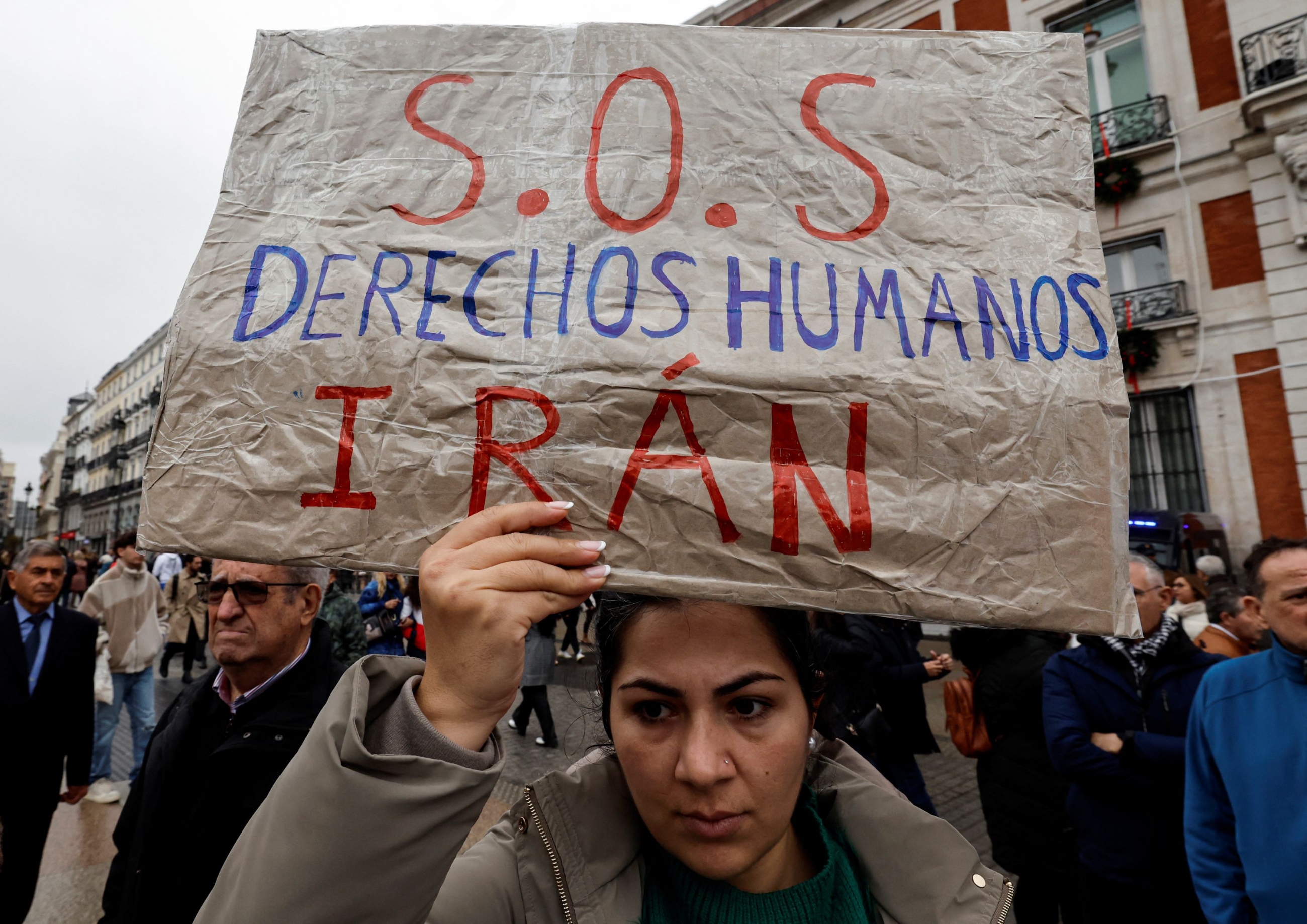 A protestor holds a sign reading "SOS Human rights Iran" during a demonstration called for the Human Rights to Peace, in Madrid, on December 10, 2023 (Oscar Del Pozo/AFP)