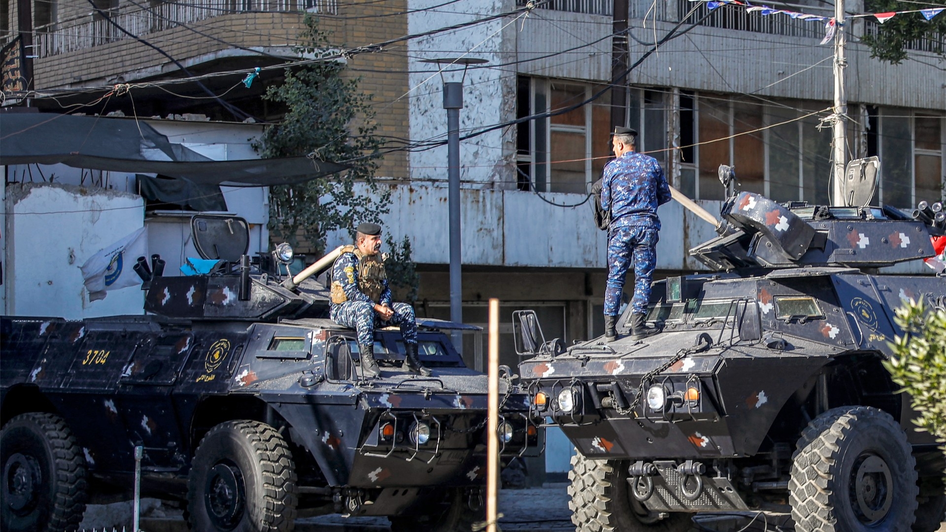 Iraqi security personnel in armoured vehicles stationed on a street in Baghdad on 26 December 2023 (AFP)