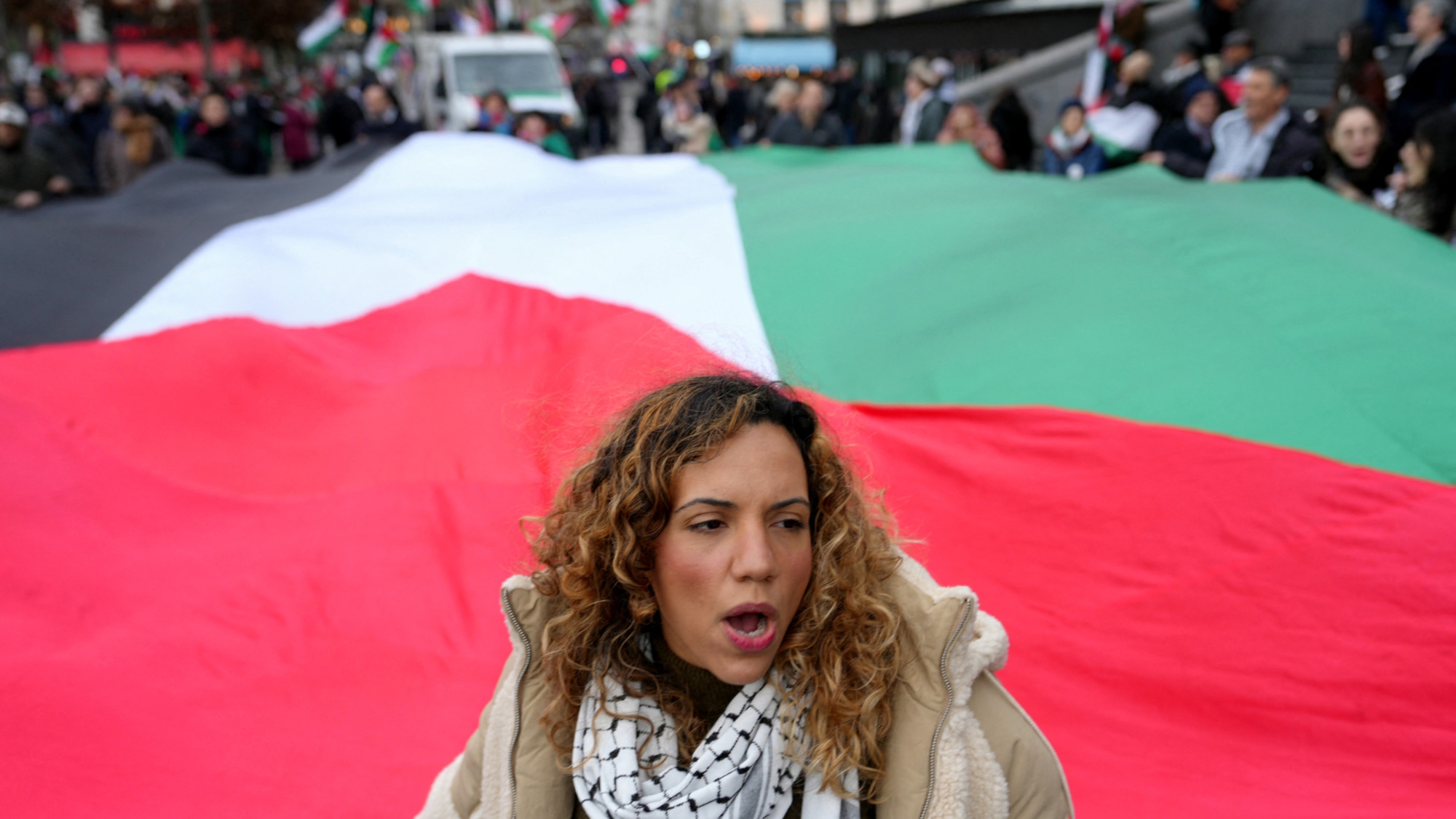 A woman holds onto the edge of a large Palestnian flag during a march in support of the Palestinian people, calling for a ceasefire at a rally in Paris on 6 January 2024 (Dimitar Dilkoff/AFP)