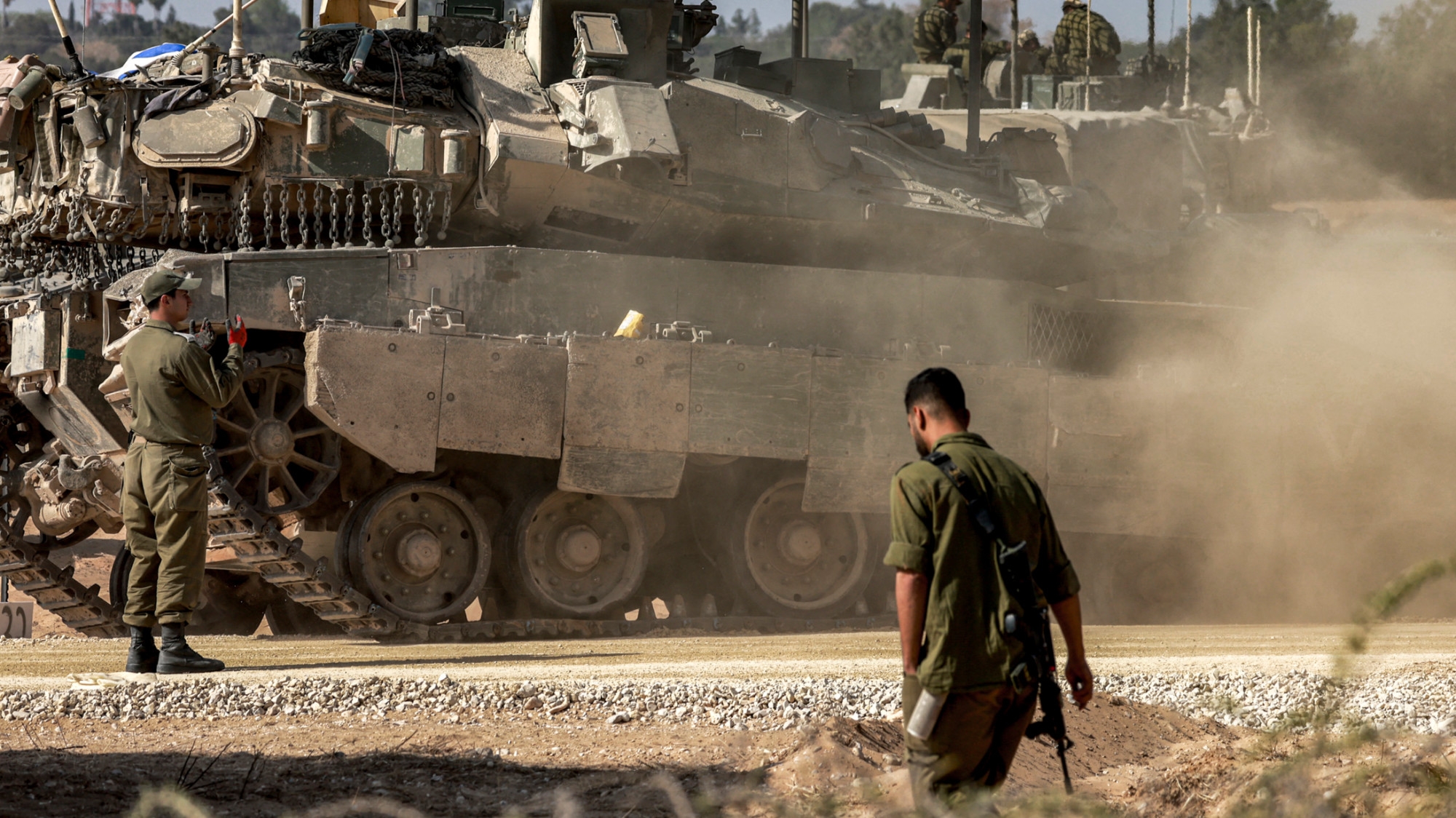 An Israeli army soldier walks past a tank as forces gather at a position near the fence with the Gaza strip in southern Israel on 30 April 2024 (AFP/Menahem Kahana)