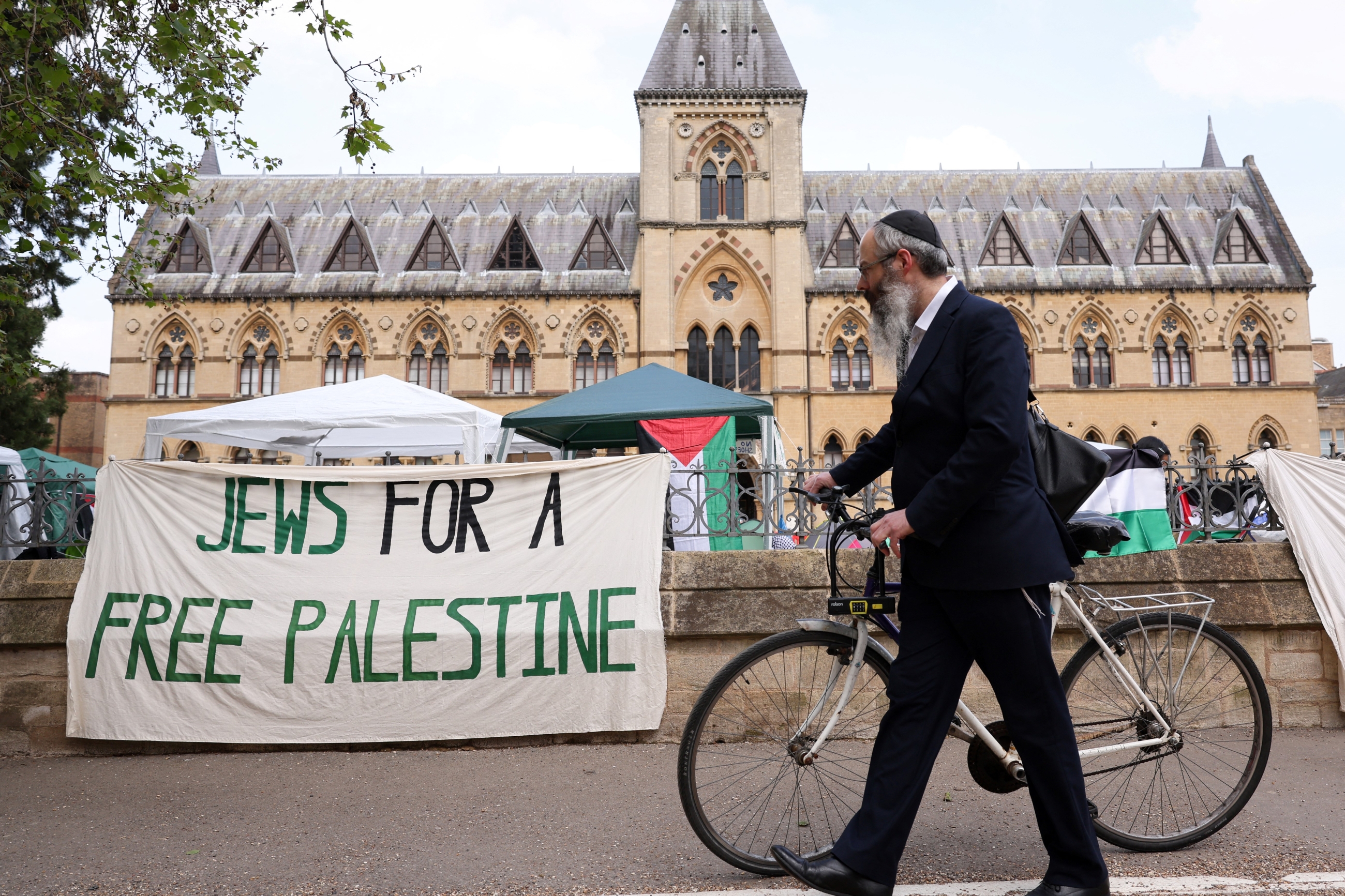 A passerby wearing a kippa pushes his bicycle past a banner reading "Jews for a free Palestine" at Oxford University in Oxford, eastern England (AFP)