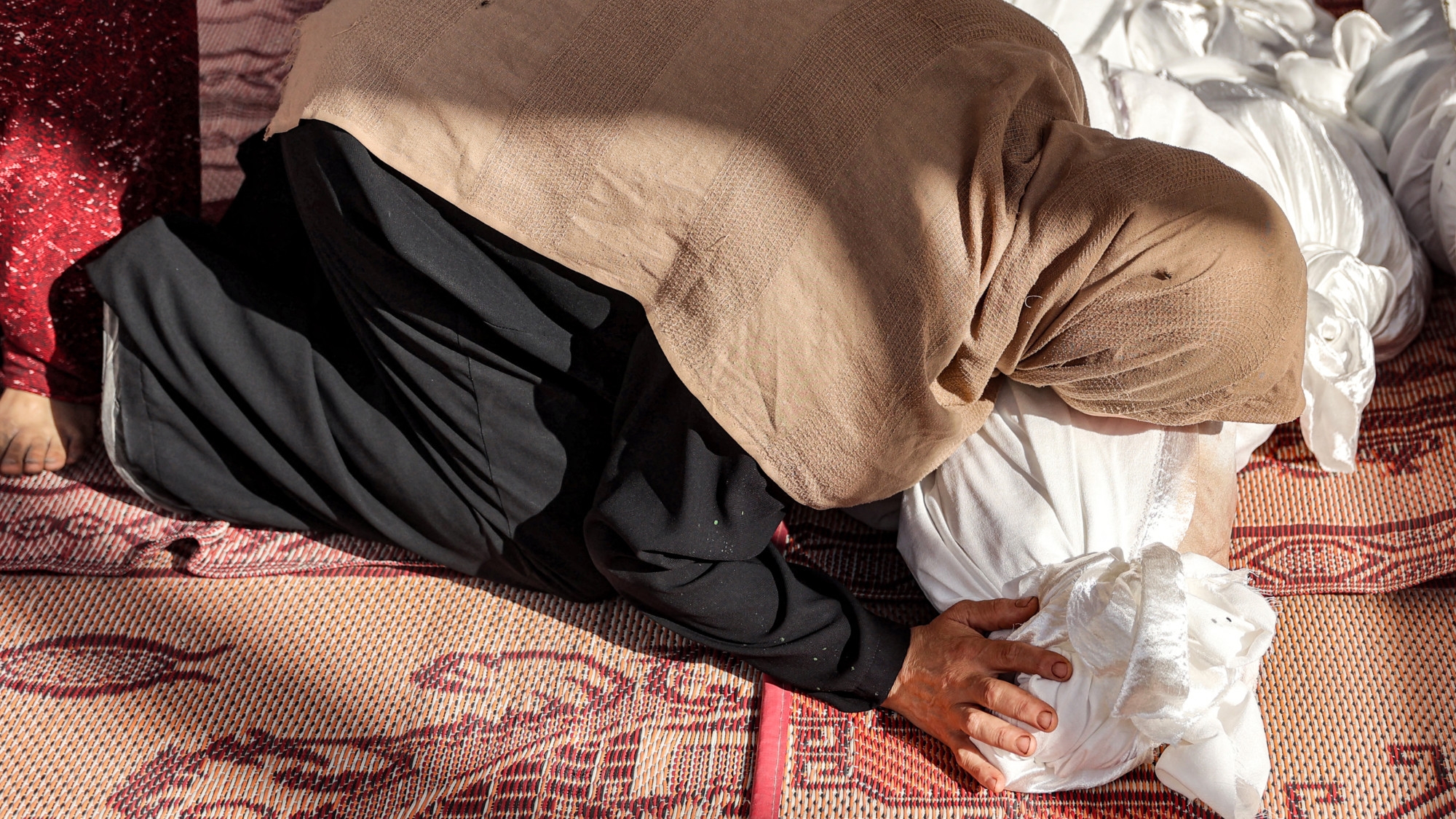 A woman mourns by one of the retrieved bodies of victims killed in overnight Israeli bombardment at the UN-run Asma school in Gaza City's al-Shati refugee camp on 25 June 2024 (AFP)