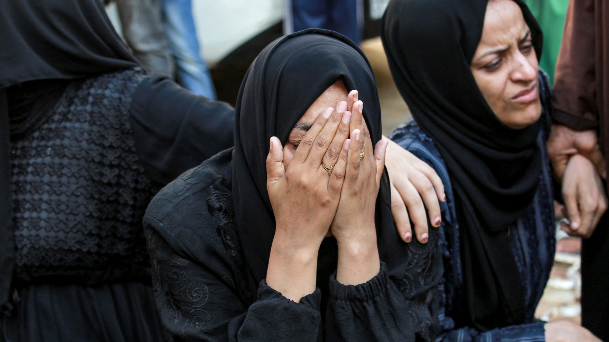 A woman sits with others gathering outside the morgue of the Aqsa Martyrs Hospital in Deir el-Balah in the central Gaza Strip on 25 June 2024 (AFP/Bashar Taleb)