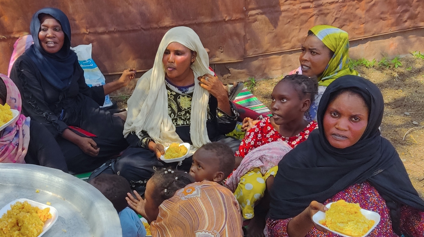 People fleeing the town of Sinja, the capital of Sudan's southeastern Sennar state, receive meals after arriving in Gedaref on 2 July 2024 (AFP)