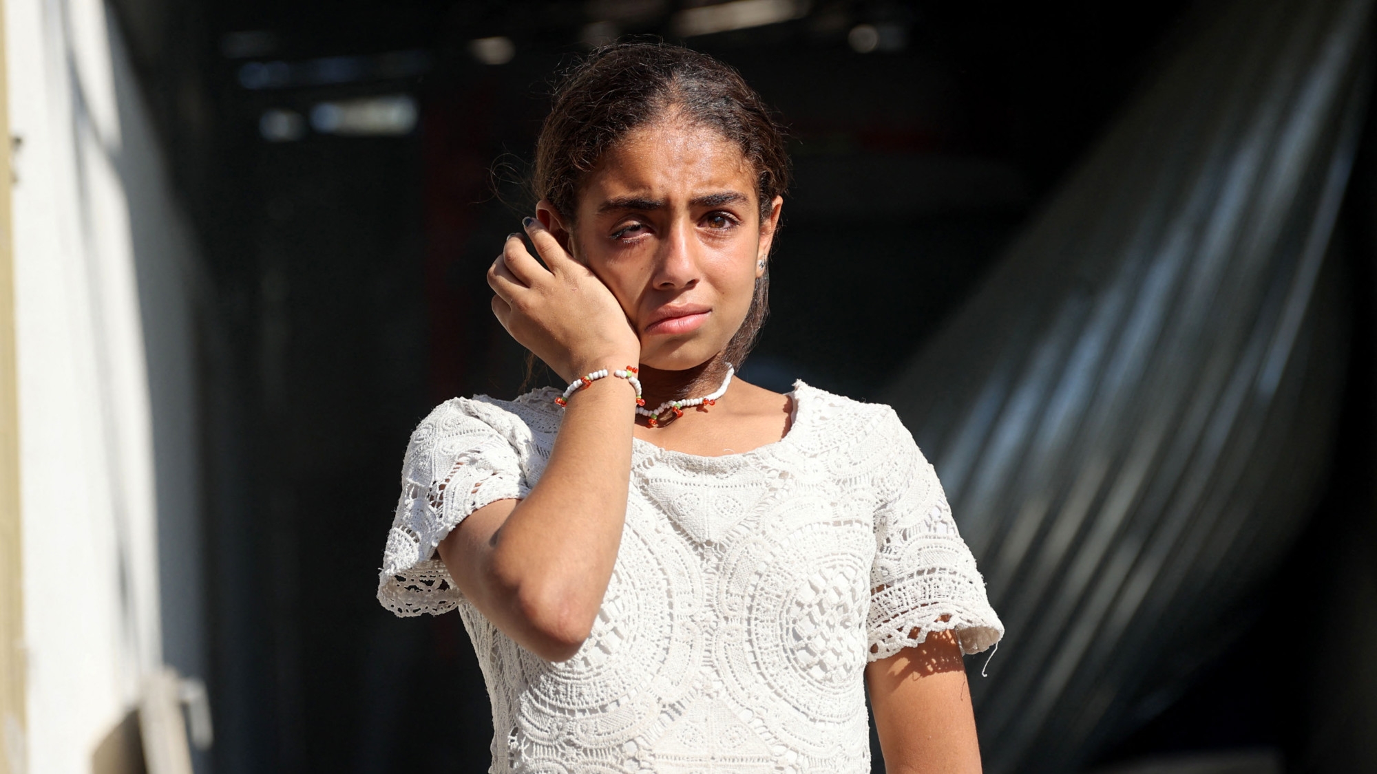 A Palestinian girl reacts as she stands in the grounds of the badly damaged Latin Patriarchate Holy Family School after it was hit during Israeli military bombardment, in Gaza City on 7 July 2024 (AFP) 