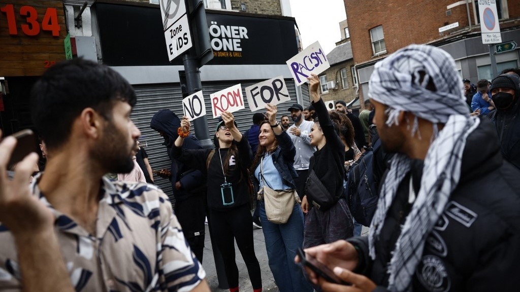 People hold signs that read 'No room for racism' during a counter demonstration against far-right riots in the Walthamstow suburb of London on 7 August (AFP)