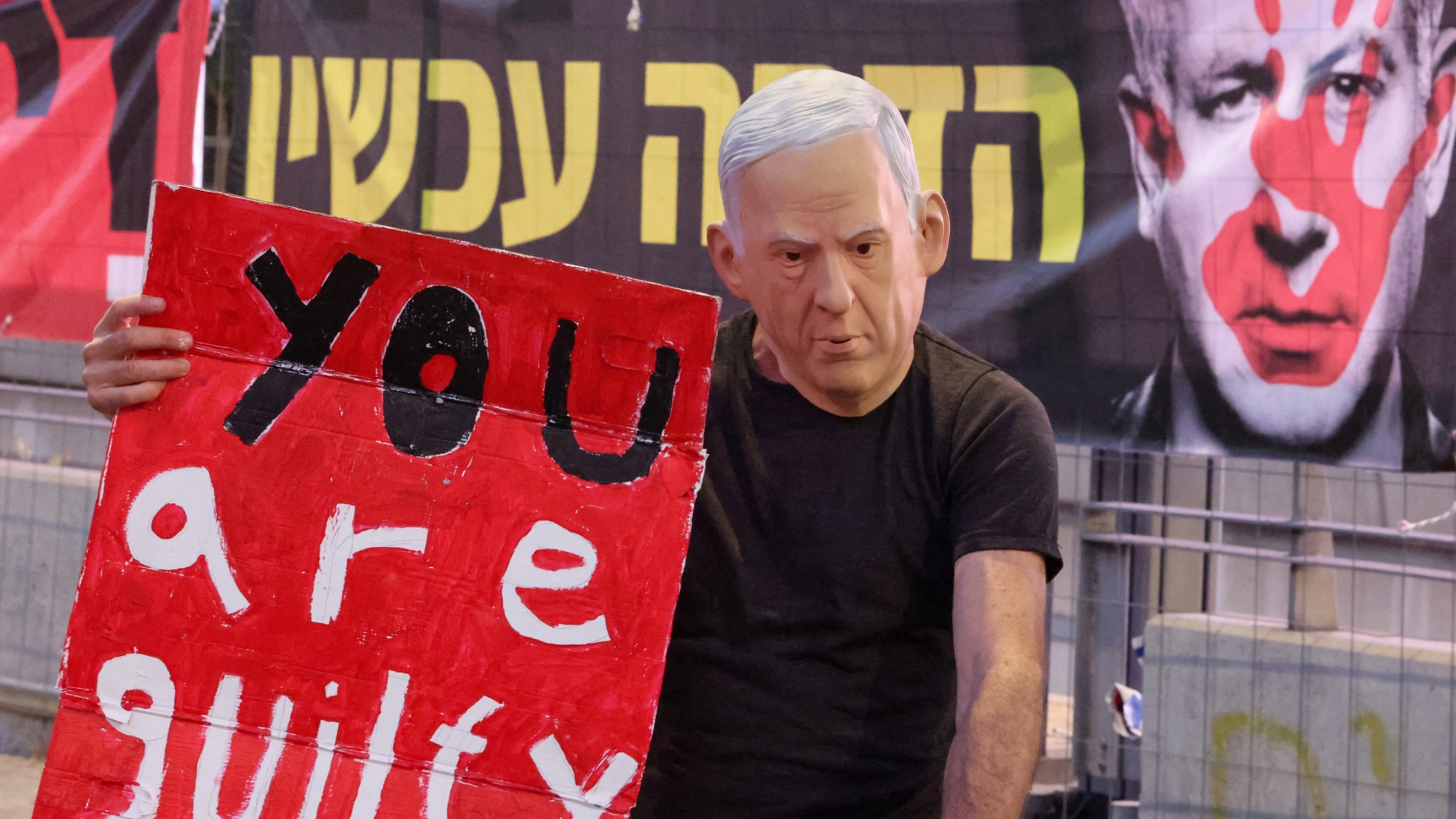 A demonstrator wearing a mask representing Israel's Prime Minister Benjamin Netanyahu lifts a placard during an anti-government protest in Tel Aviv on 31 August 2024 (AFP/Jack Guez)