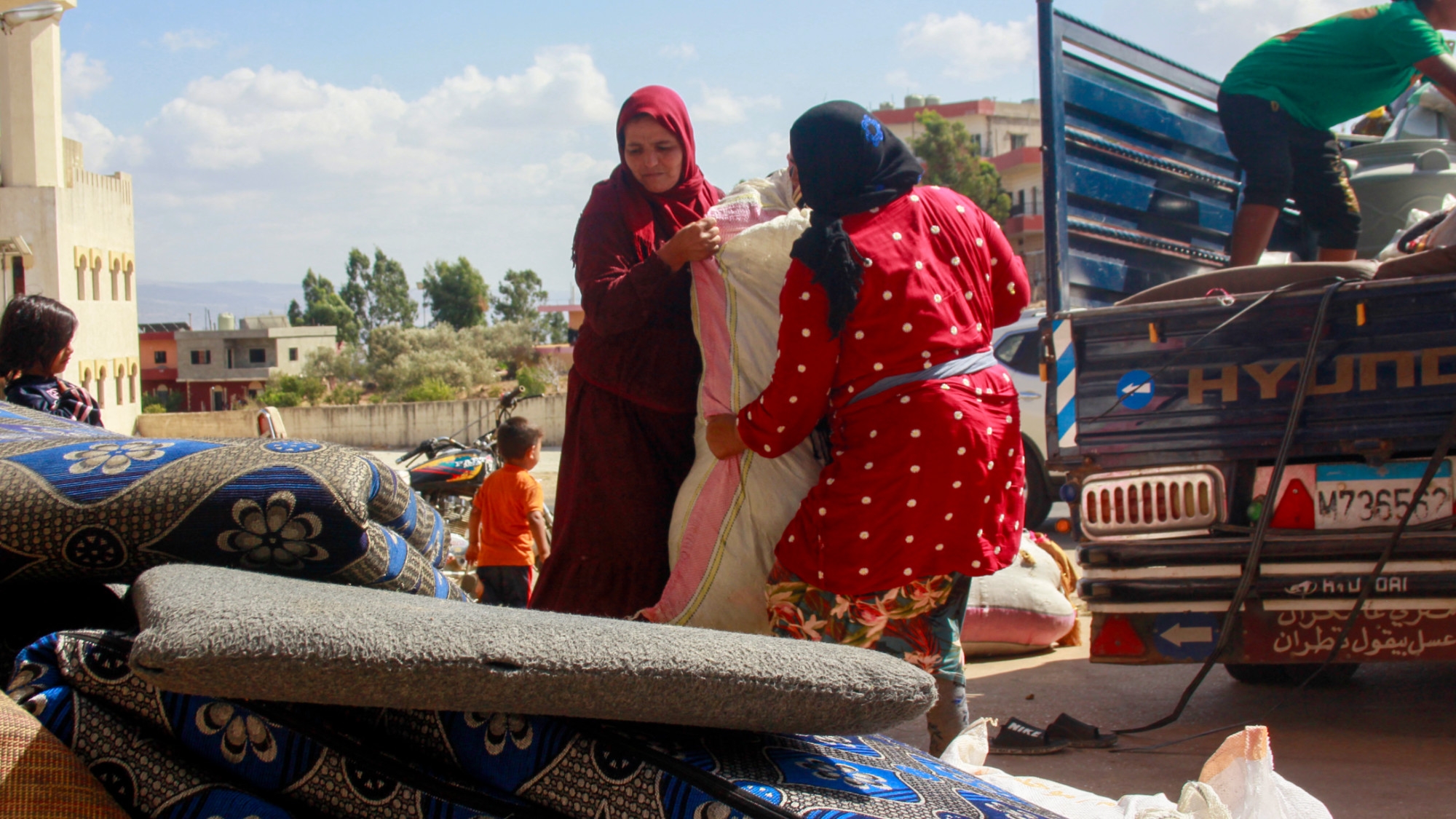 Syrian refugees load their belongings on a truck as they prepare to leave the southern Lebanese village of Wazzani after the Israeli army dropped leaflets calling for them to evacuate on 15 September 2024 (AFP/Rabih Daher)