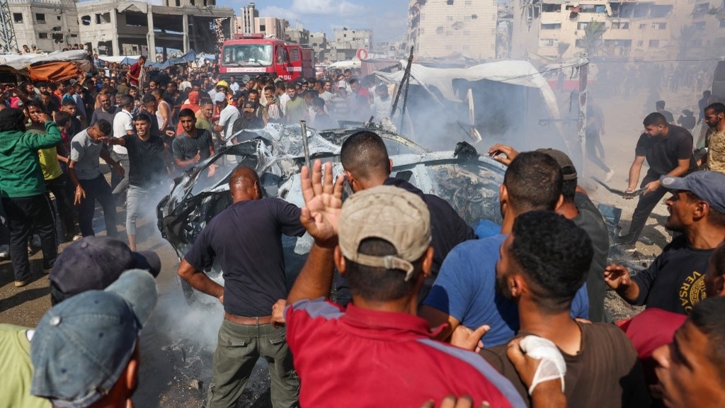 Displaced Palestinians douse a burning car with water after it was hit in an Israeli strike in Khan Yunis in the southern Gaza Strip city on 1 October 2024