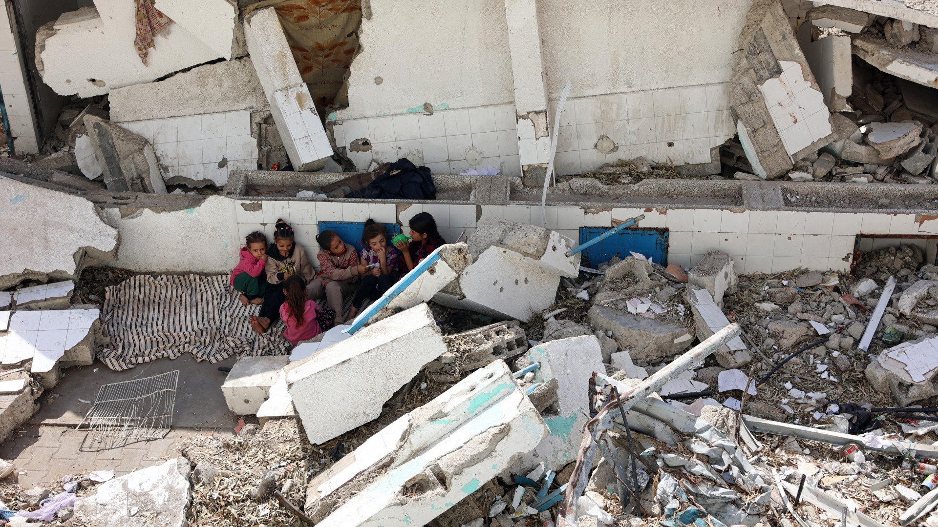 Displaced Palestinian children sit amid the rubble of a destroyed building in the Nasser district of Gaza City in the northern Gaza Strip, on 25 October 2024 (Omar Al-Qattaa/AFP)