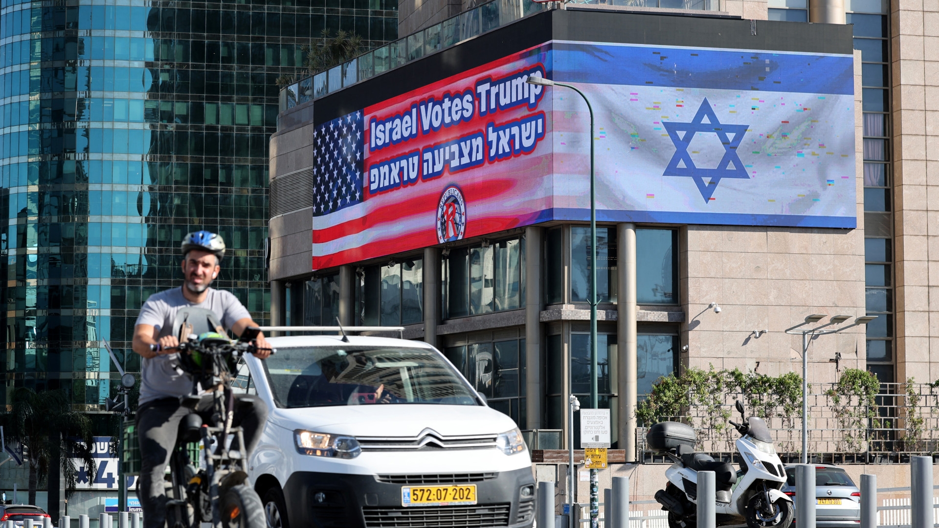 Commuters drive past a billboard bearing the flags of the US and Israel with a message supporting US presidential candidate Donald Trump in Tel Aviv on 30 October 2024 (Jack Guez/AFP)