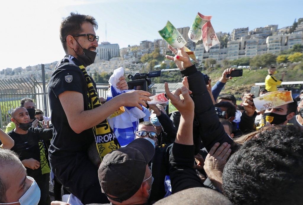 Une personne jette de l’argent à Moshe Hogg, propriétaire du club de football israélien Beitar, lors de la séance d’entraînement du club à Jérusalem, le 11 décembre 2020 (AFP)